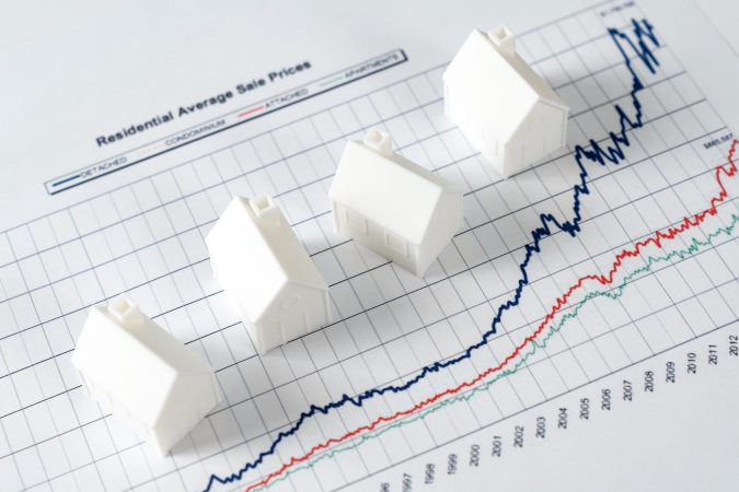 White miniature house models on graph indicating growth in real estate prices market