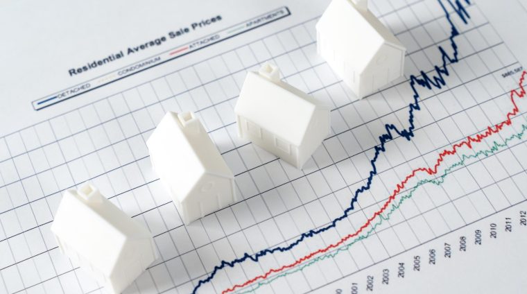 White miniature house models on graph indicating growth in real estate prices market