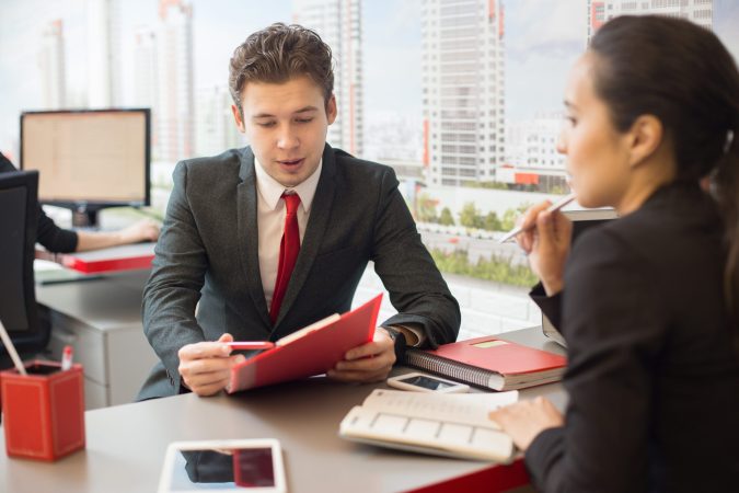 Portrait of young businessman talking to colleague discussing work during meeting in real estate agency