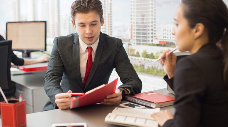 Portrait of young businessman talking to colleague discussing work during meeting in real estate agency