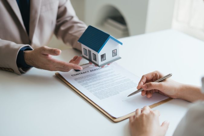 Real estate agent and realtor general liability insurance businessman professional discussing and consultant with house toy model building before sign a contract with law concept.